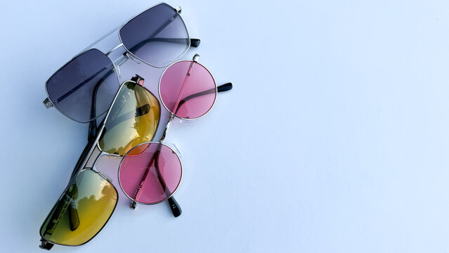 Three pairs of modern sunglasses with tinted lenses arranged on a plain background, eyewear collection, summer fashion.
