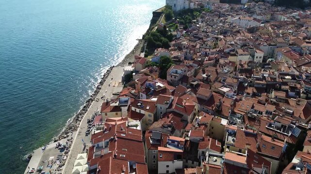 Aerial view of St. George&rsquo;s Parish Church in Piran, Slovenia, featuring its historic bell tower and surrounding old town architecture on the Adriatic coast under a sunny summer sky.