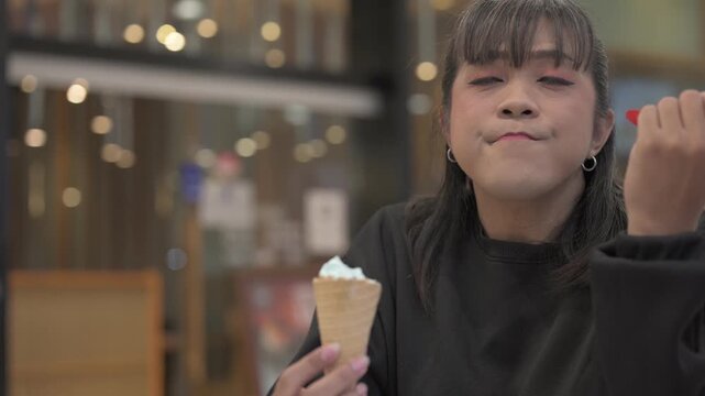 Asian Person Eating Ice Cream Cone Indoors with Spoon