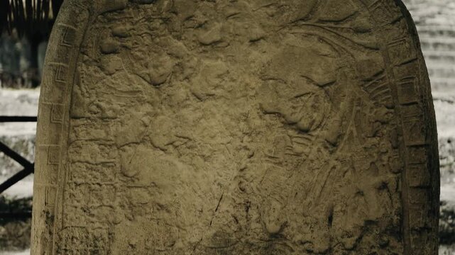 Close-up of a carved limestone Mayan stela near Temple I (El Gran Jaguar) at Tikal, Guatemala. Steady daylight shot highlights detailed glyphs, weathered textures, and historical presence.