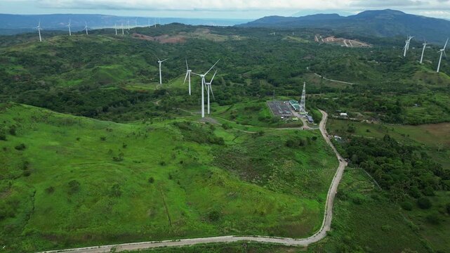Scenic aerial view of wind turbines on green hills in Pililla, Rizal during daytime with a tropical mountain backdrop.