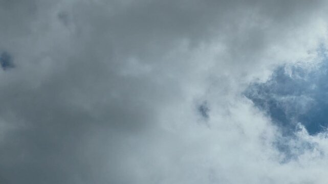 Ominous grey storm clouds drifting across a patch of blue sky on a dramatic, windy day