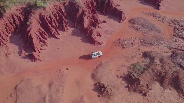 4WD Weaving between Steep Red Rock Walls on Narrow Sandy Track at James Price Point Australia, Aerial Drone Shot