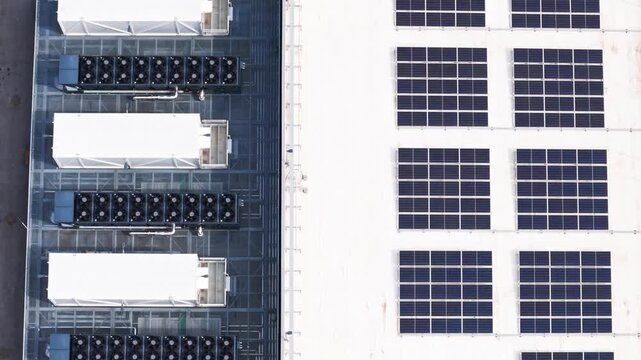 Top-down aerial view of a large data center roof with photovoltaic solar panels for renewable energy and industrial air conditioning units