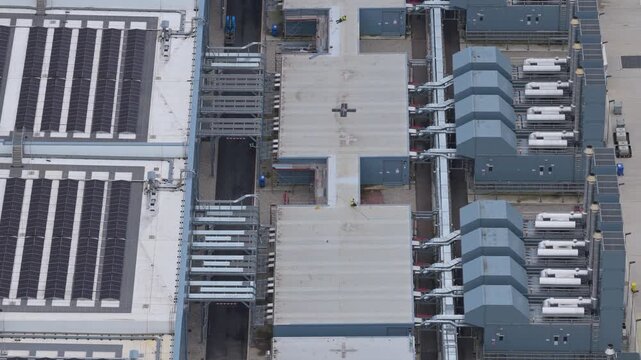 Top down aerial perspective of a large, modern hyperscale data center, revealing its complex rooftop cooling systems and advanced infrastructure