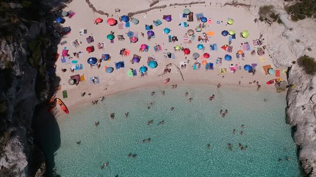 Crowded Beach with Colourful Umbrellas Top Down Aerial Drone View of Cala Macarelleta Menorca Spain