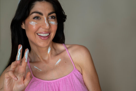 Beautiful  Smiling Woman applying sunscreen lotion on her face