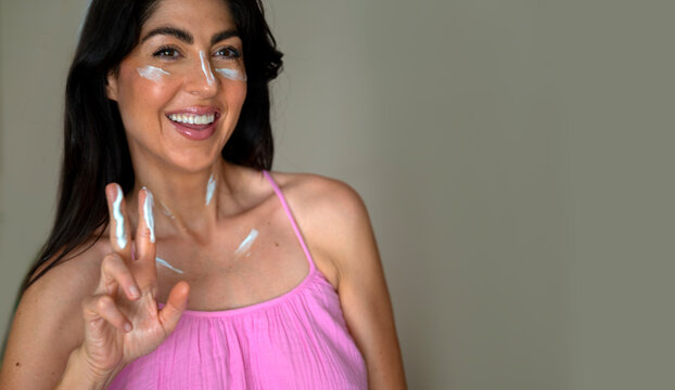 Beautiful  Smiling Woman applying sunscreen lotion on her face