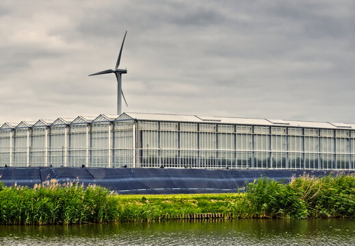 Modern greenhouse complex with solar panels and a wind turbine symbolizing sustainable agriculture and renewable energy