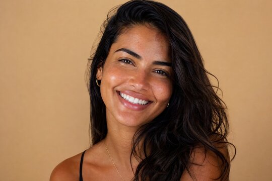 Retrato de uma linda mulher brasileira sorrindo com pele saud&aacute;vel e iluminada, dentes brancos e beleza natural. Fundo begeю