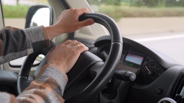Man's hands gripping the steering wheel while driving a camper van on the highway for a road trip holiday, showing the dashboard and the moving roadside scenery through the side window