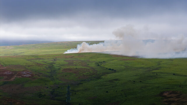High angle view of moorland fire smoke spreading across dry upland grass, extreme weather conditions threatening natural habitats during summer drought