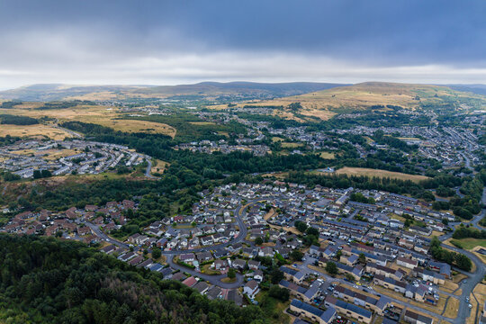 Residential housing developments in a Welsh valley, parched countryside and yellowed grass from warm dry summer weather, high angle view