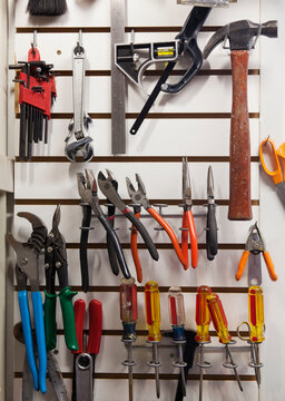 Tools on a rack on a white wall, in a workshop, neat storage.