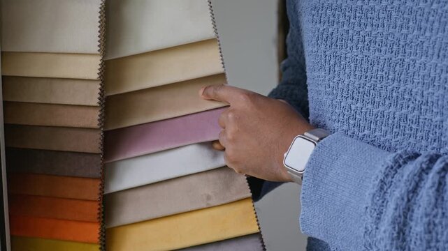 African American man choosing upholstery fabric from colorful palette swatches. Footage is suitable for interior design promos, home renovation ads, and furniture store marketing