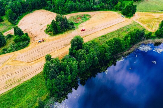 Aerial view of farmland with freshly plowed fields, lush greenery, and a calm lake in Finland