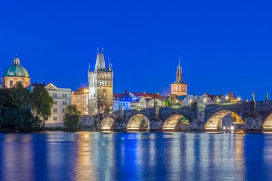 The Charles Bridge over the River Vtlava with buildings lit up at night.