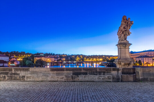 The Charles Bridge at Dawn, a statue and view over the calm river water.