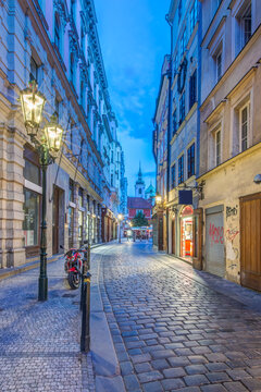 Narrow street in the Old Town at night or dawn, cobbles and buildings, and a small motorcycle.