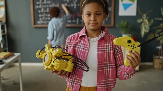 Portrait of African American teenager holding yellow robotic submarine and remote controller in classroom. Video is ideal for promoting STEM education, school robotics, and modern learning