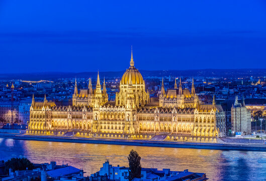 Budapest, the Hungarian Parliament building, Orsz&aacute;gh&aacute;z, neo-Gothic architecture, dome and stone pinnacles, lit up at dusk, by the River Danube.