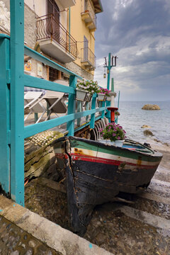 Fishing Boat tied up to a fence on a slipway by the sea shore.