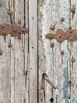 Weathered Door, close up of a cracked worn wooden door with deep cracks, metal hinges and nails