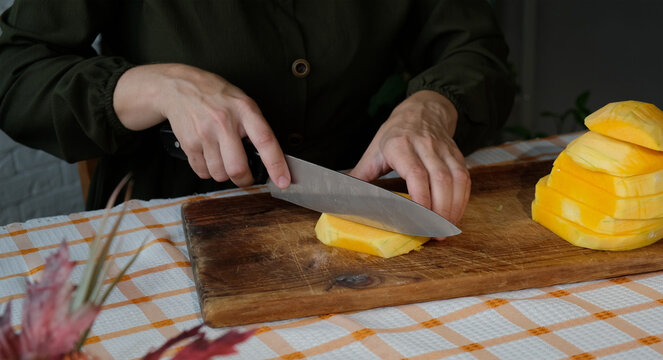 Female hands slicing pumpkin. Preparing autumn food. Cooking pumpkin soup or cake.
