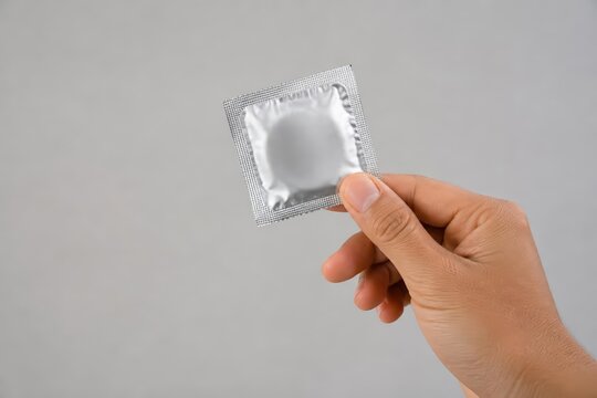 Hand holding silver condom packet