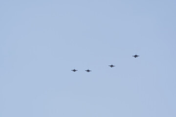 Fototapeta premium Four military jet aircraft flying in a formation in a clear blue sky