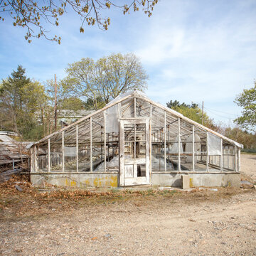 A derelict greenhouse on a farm, ripped plastic sheeting and missing or broken glass, the property demolished in 2015.