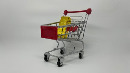 Side view of mini shopping cart loaded with gold bars on grey background © fuad chasan