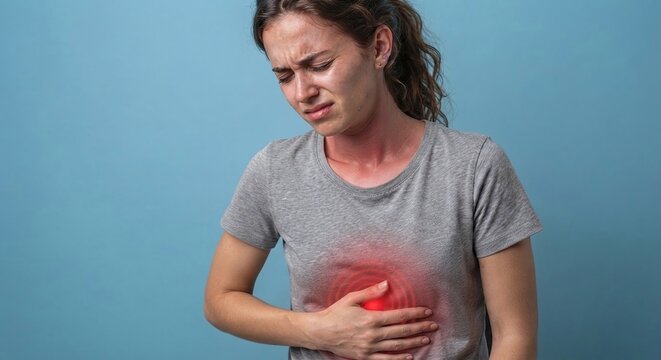Young woman suffering from stomach pain, heartburn or indigestion holding her abdomen