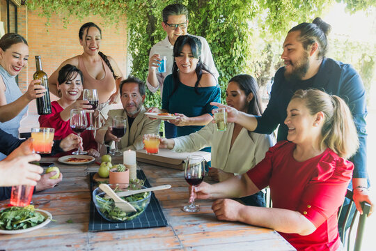 large group of latinos friends or multi generation family eating pizza and having a dinner in a terrace party in Mexico Latin America, hispanic diverse, multi age and multicultural people