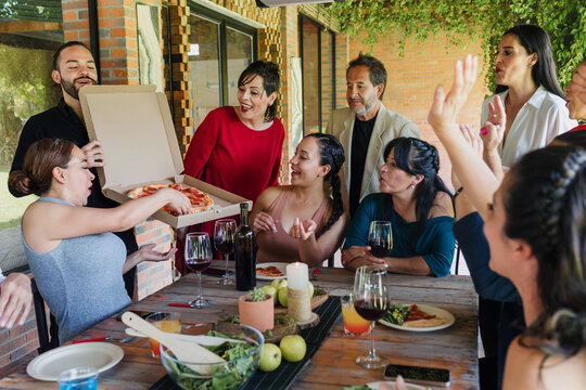 large group of latinos friends or multi generation family eating pizza and having a dinner in a terrace party in Mexico Latin America, hispanic diverse, multi age and multicultural people