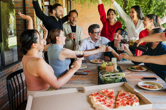 large group of latinos friends or multi generation family eating pizza and having a dinner in a terrace party in Mexico Latin America, hispanic diverse, multi age and multicultural people