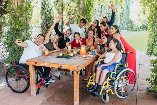 large group of friends with people with disabilities and wheelchair eating and having a dinner in a terrace party in Mexico Latin America, hispanic diverse and multicultural people 