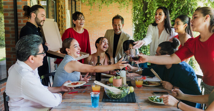large group of latinos friends or multi generation family eating pizza and having a dinner in a terrace party in Mexico Latin America, hispanic diverse, multi age and multicultural people