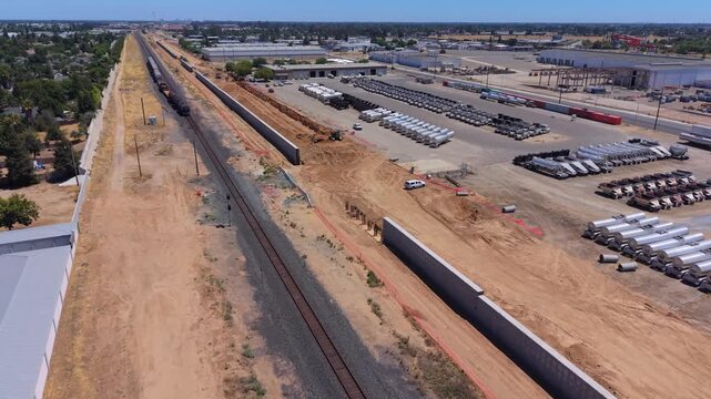 Still Aerial Drone Shot Over Train Track With Train Passing California High Speed Rail Construction Intrusion Barrier Walls Excavator Digging and Neighborhoods in Fresno California
