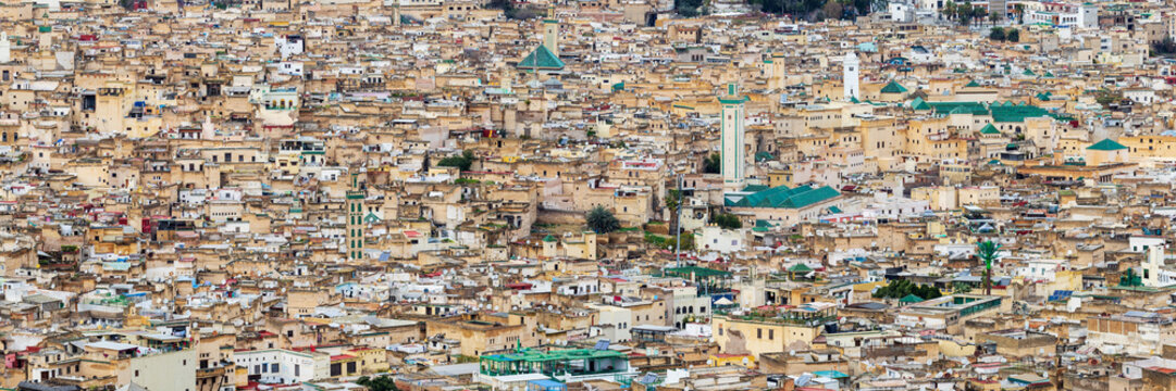 Elevated view of the buildings of the Medina at Fes, closely packed buildings, wind towers and mosque minarets, small historic buildings.
