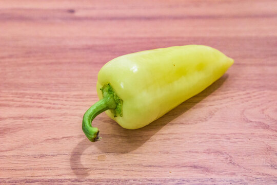 A single Hungarian white wax pepper, also known as TV paprika or t&ouml;lteni val&oacute;, lying on a wooden table.