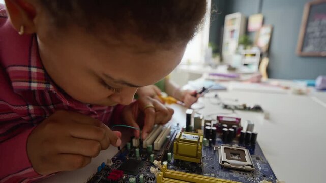 African American teenager girl connecting wires to computer motherboard during STEM class in modern school. Video is ideal for promoting technology education and diversity in science