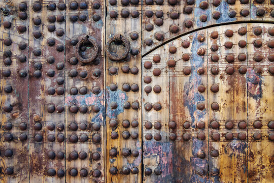 A wooden doorway in an old building with metal studs, close up
