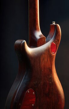 Close-up of the back of an electric stringed musical instrument. Brown wood grain visible