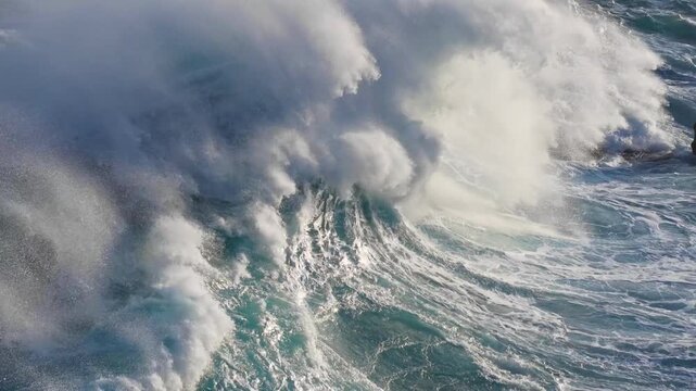 Powerful ocean wave breaking with white foam and spray in deep blue sea, massive stormy wave collapses in open ocean. Huge ocean wave crashing in stormy sea with splash and foam