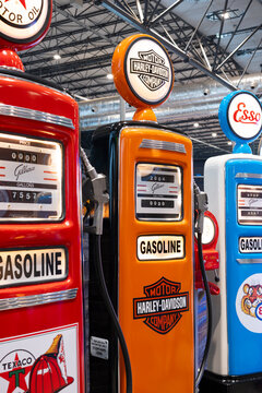 Restored vintage fuel pumps from Texaco, Harley-Davidson, and Esso brands on display with internal lighting and hoses.