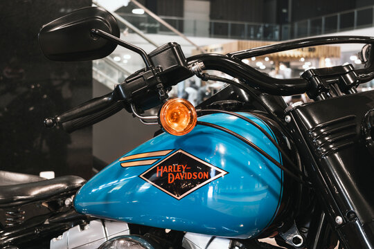 Close-up of a Harley-Davidson cruiser showcasing turquoise bodywork, black handlebars, and classic fuel tank emblem.