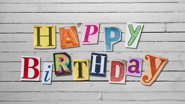 Stop motion animation of Happy Birthday text made from magazine cutout letters over wooden table