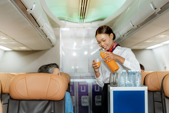Professional cabin crew serving fresh juice to a passenger during a commercial flight highlighting premium airline hospitality comfort and outstanding customer experience

