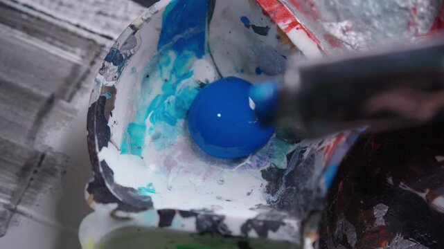 Macro Close Up View of Squeezing Blue Watercolor Paint from Tube onto Palette and Mixing with Brush